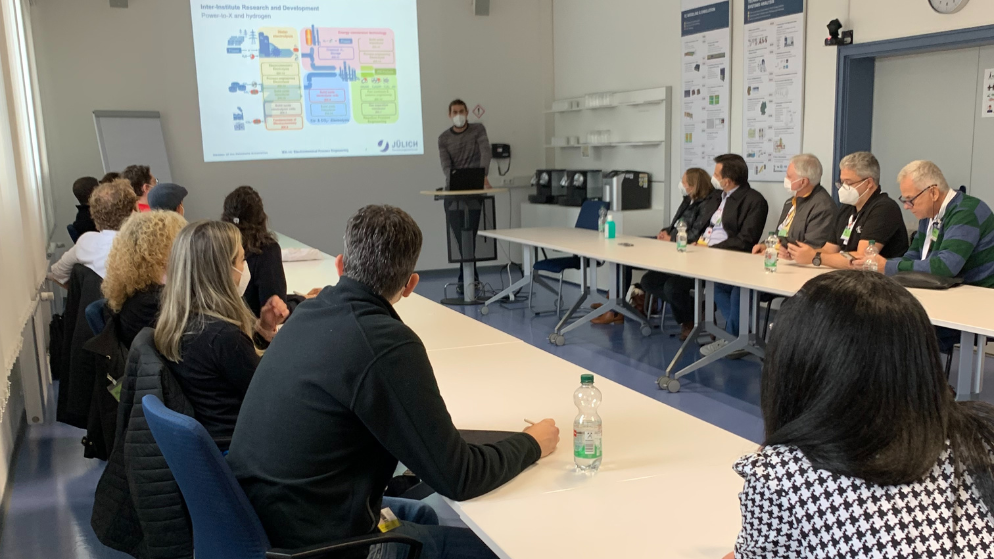 All the participants of the R&D Tour are sitting around a table and listen to a presentation at the Research Center Jülich.
